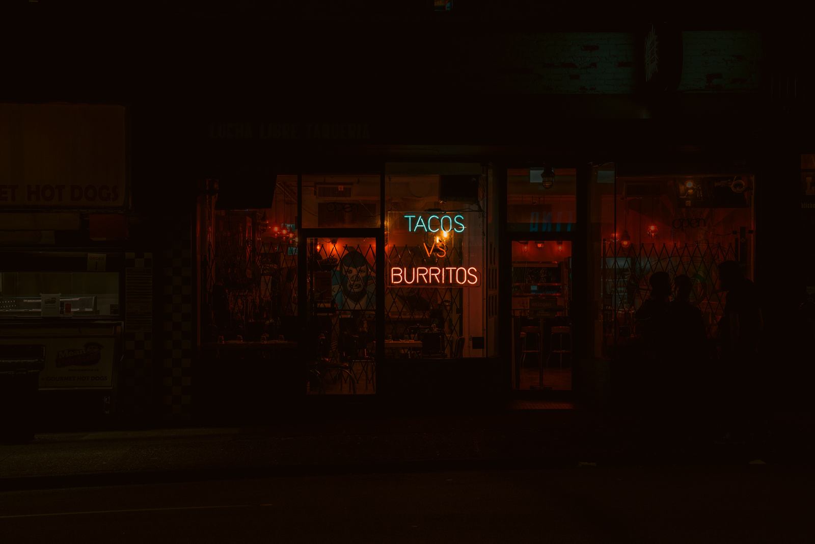 Neon tacos vs burritos storefront at night